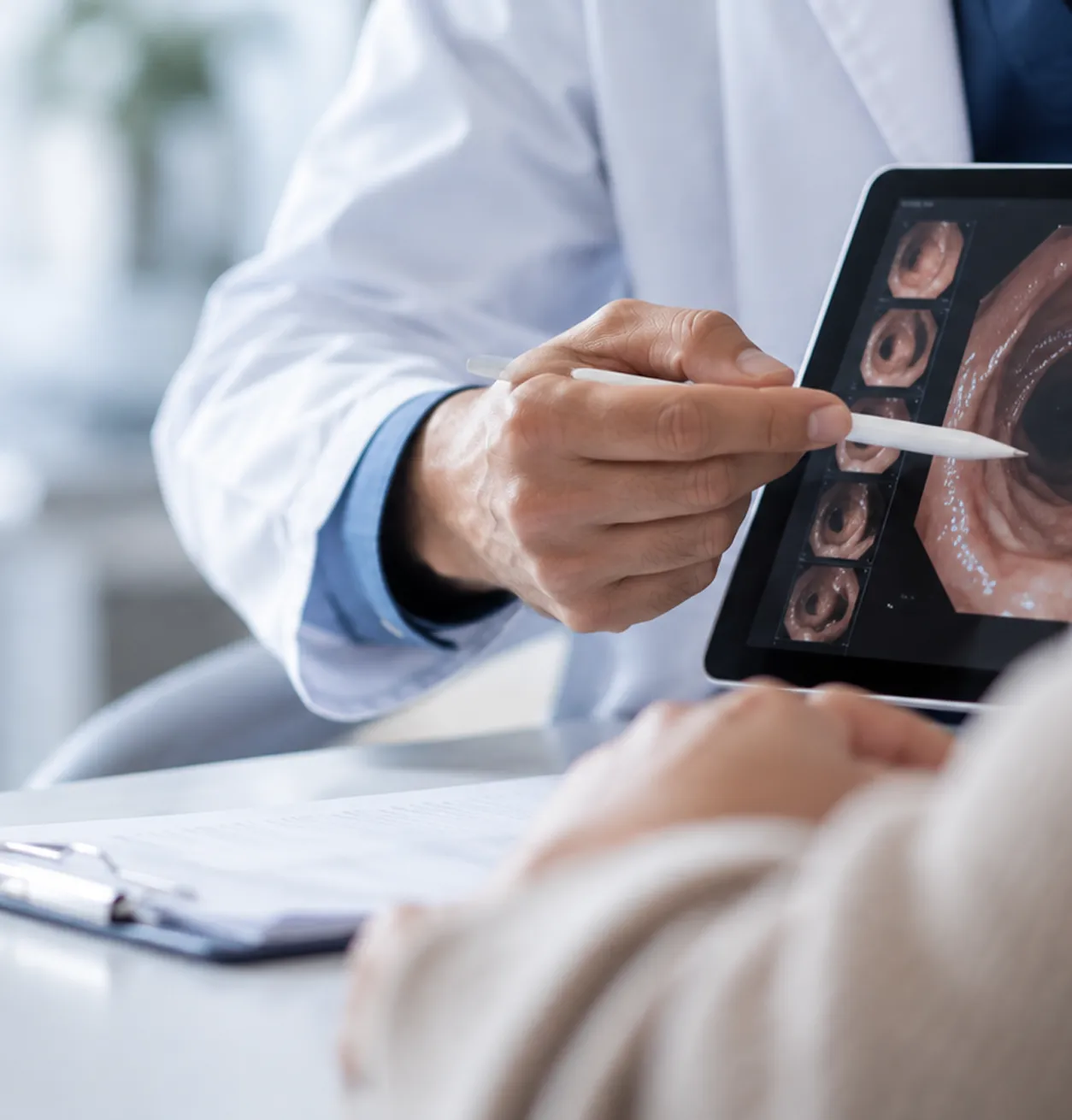 Profesional de gastroenterología explicando un estudio endoscópico durante una consulta médica.